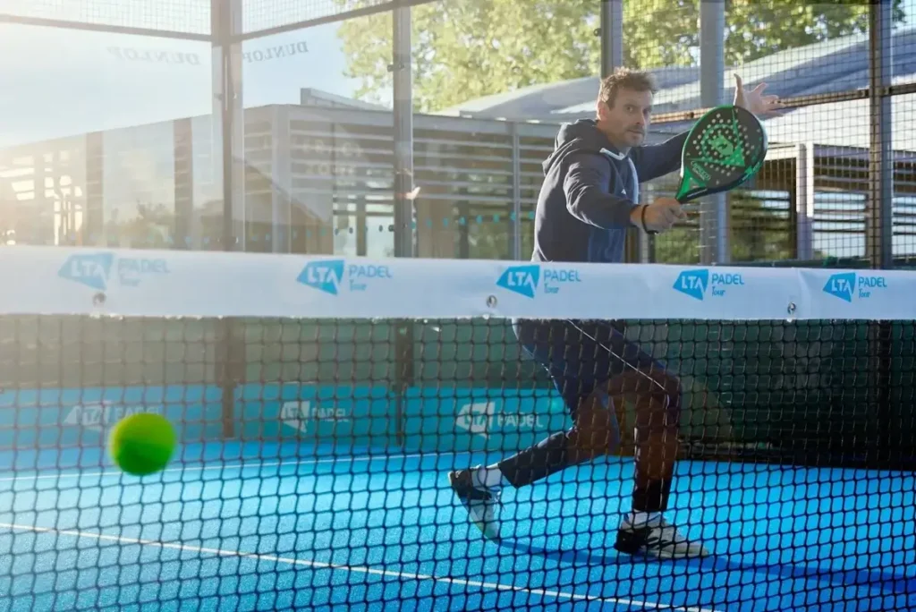 A player mishitting a ball using a tennis racket during a padel game, showing the difficulty of control